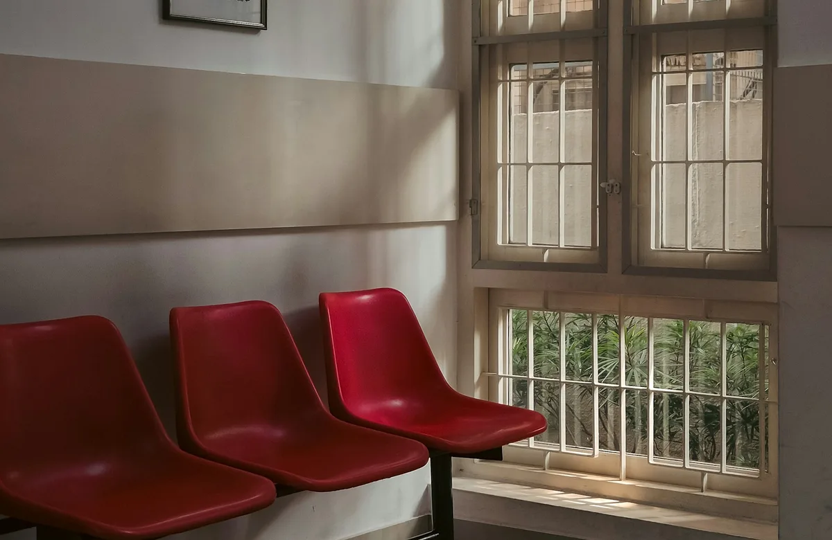 Ruhiger Wartebereich mit roten Stuehlen am Fenster als Referenzbild fuer die Privatpraxis Dr. Weber
